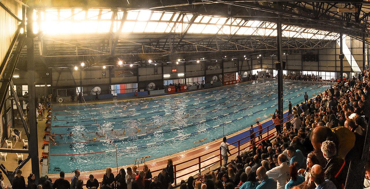 A packed swimming hall with spectators watching a race